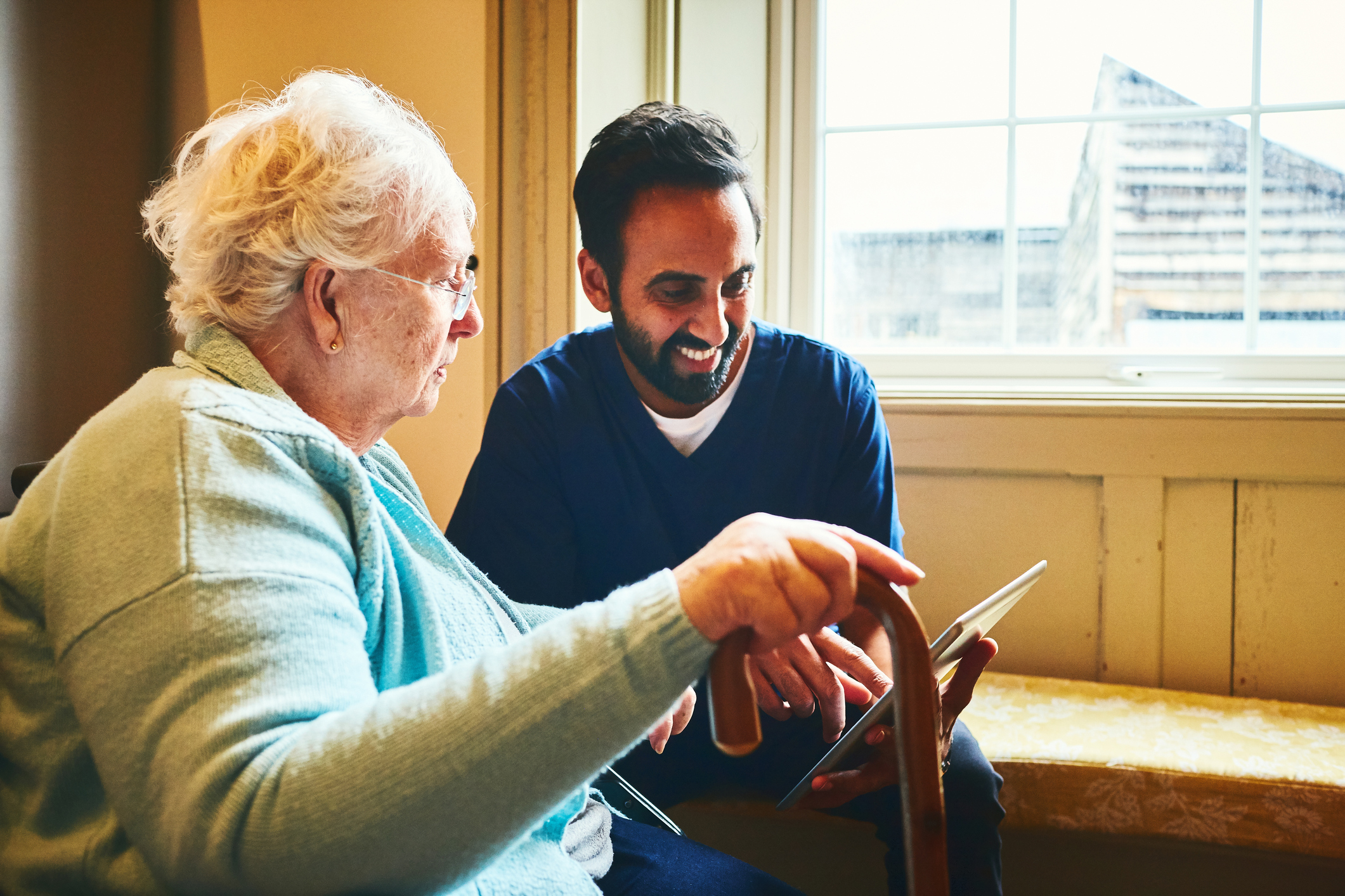 Younger person working with an older lady to show her how to use a tablet Younger person working with an older lady to show her how to use a tablet