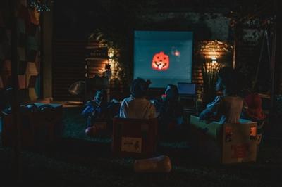 Kids watching Halloween movie on screen in backyard