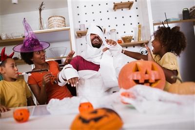Parents and two young children dressing up and preparing for Halloween