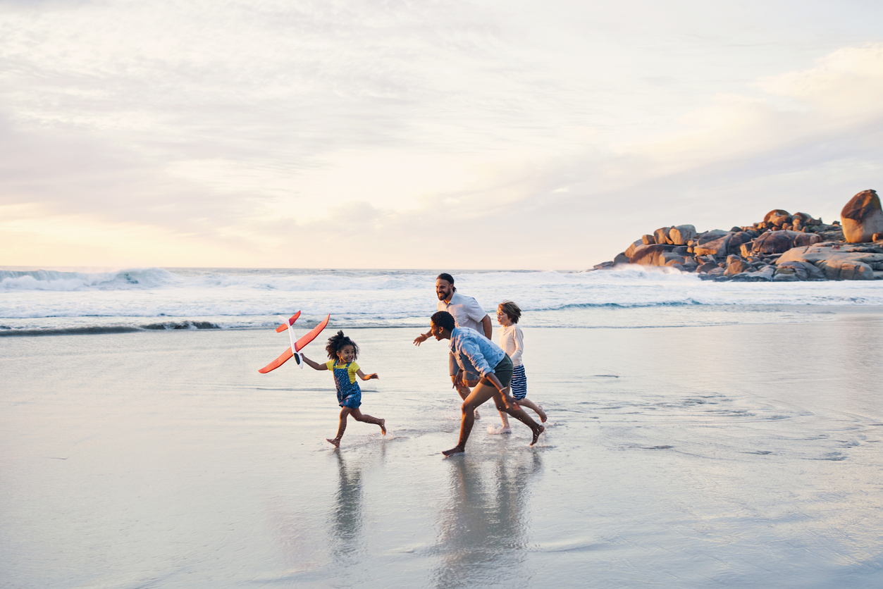Man running on beach with his three children.