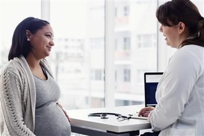 Pregnant woman talking with doctor in her office