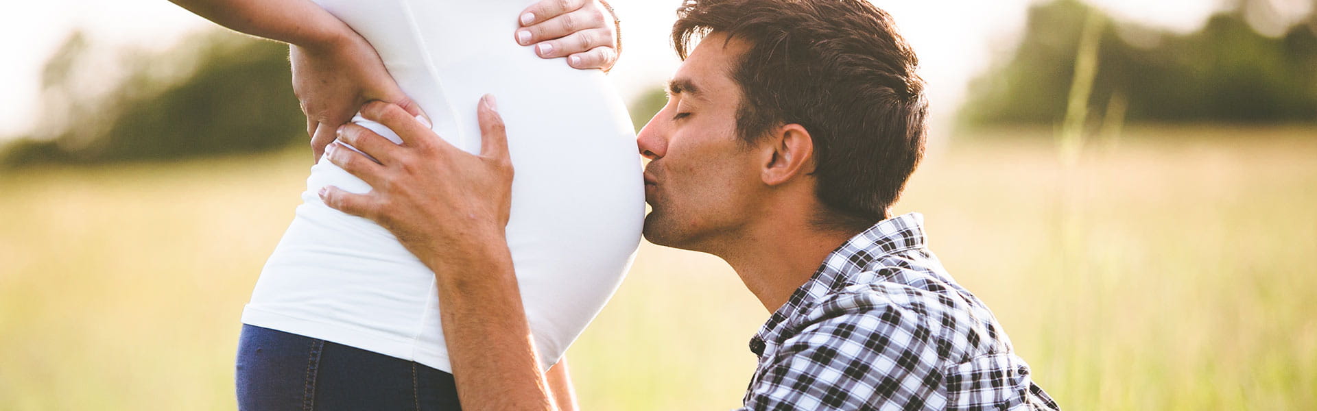 man kissing womens pregnant belly