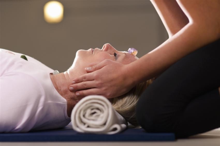 Young therapist arranging crystals on female client for reiki