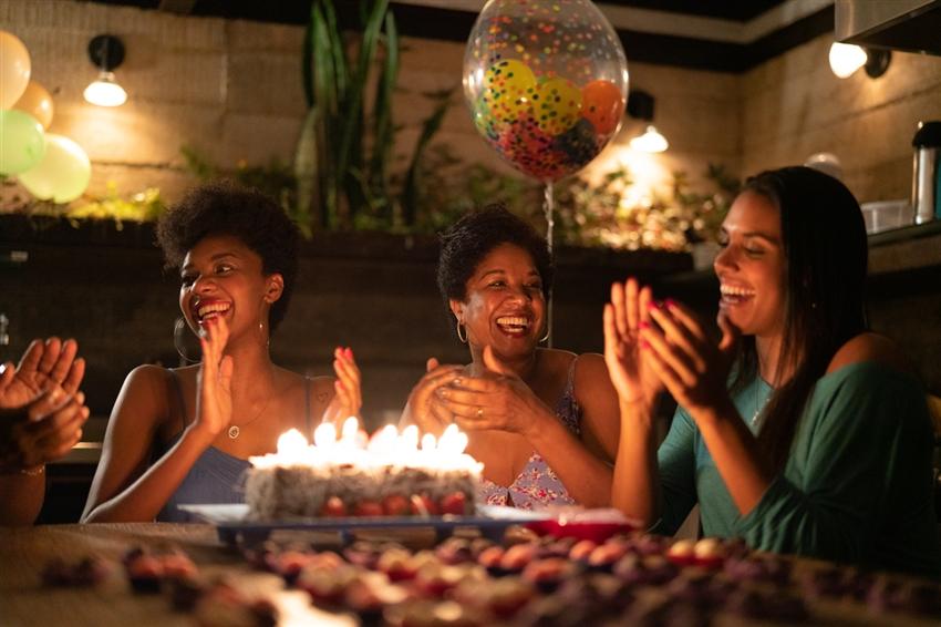 People celebrating at home with a cake with lit candles